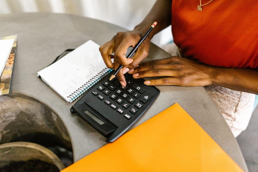 Hands working a calculator over a notebook